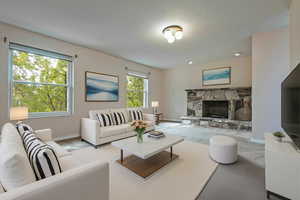 Carpeted living room with a stone fireplace and baseboards