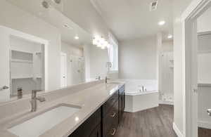 Full bath featuring a stall shower, a bath, dark wood-style floors, double vanity, and recessed lighting