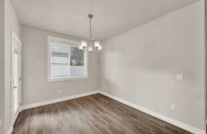 Unfurnished dining area with wood finished floors and a chandelier
