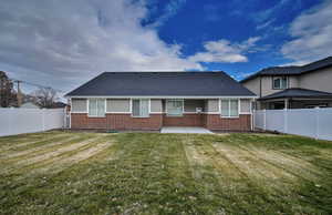 Rear view of house featuring a fenced backyard, a patio area, and a shingled roof