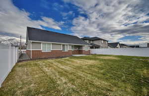 Rear view of property with a fenced backyard, a patio, brick siding, and a shingled roof