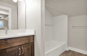 Bathroom with vanity, dark wood-style flooring, and shower / bathtub combination