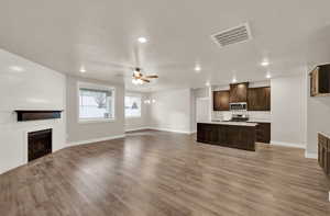 Unfurnished living room featuring a fireplace, ceiling fan, light wood-style floors, recessed lighting, and a textured ceiling