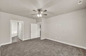Unfurnished bedroom featuring carpet, ensuite bathroom, and a ceiling fan