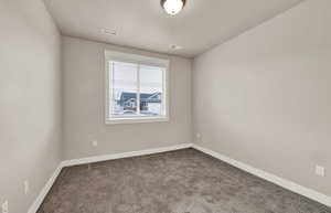 Carpeted spare room featuring baseboards