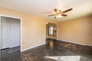 Empty room featuring a ceiling fan, dark wood-style floors, and a textured ceiling