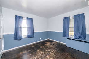 Spare room featuring baseboards and dark wood-type flooring
