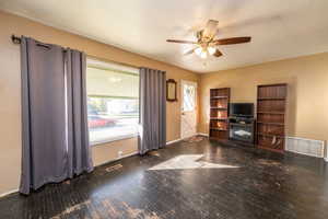 Living room with dark wood-style floors and a ceiling fan