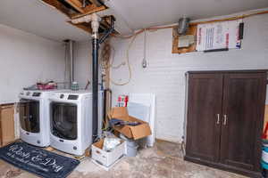 Washroom with unfinished concrete flooring and washing machine and clothes dryer