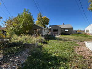 Rear view of property with a patio and a vegetable garden