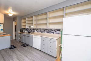 Kitchen featuring white appliances, light countertops, open shelves, gray cabinetry, and light wood finished floors