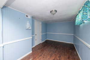 Spare room featuring dark wood-type flooring and a textured ceiling