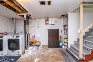Unfinished below grade area featuring stairs and washing machine and dryer