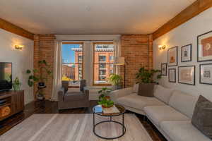Living room with wood beams, large Pella windows and a brick wall