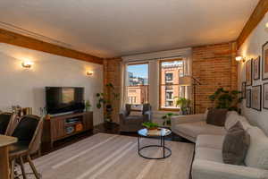 Living room with wood floors and a brick wall, sconce wall lighting