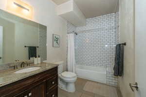 Re- tiled Bathroom shower / bath combination, wooden vanity and light tile floors