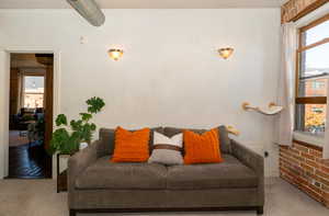 Carpeted 2nd bedroom with a brick wall and east facing window