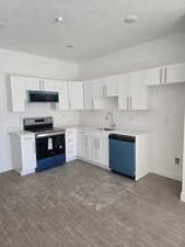 Kitchen featuring white cabinets, stainless steel appliances, dark wood-style floors, light countertops, and a textured ceiling