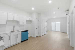 Kitchen featuring white cabinetry, dishwashing machine, light wood-style floors, recessed lighting, and light stone countertops