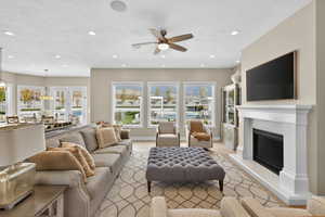 Living area with a textured ceiling, a glass covered fireplace, recessed lighting, and a ceiling fan