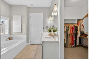 Bathroom with double vanity, a garden tub, and a spacious closet