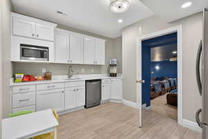 Kitchen featuring white cabinetry, light wood-style flooring, appliances with stainless steel finishes, recessed lighting, and light stone countertops