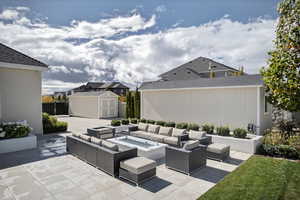 View of patio featuring an outdoor living space with a fire pit and a shed