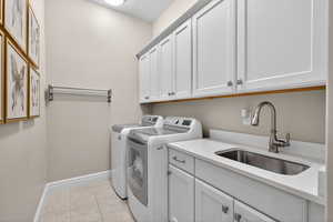 Laundry room with washing machine and dryer, cabinet space, and light tile patterned flooring