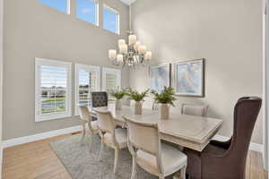 Dining space with light wood finished floors, a high ceiling, and a chandelier
