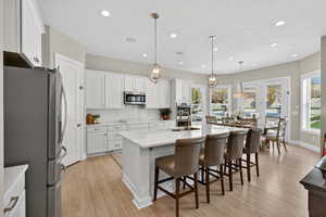 Kitchen with appliances with stainless steel finishes, a kitchen island with sink, backsplash, a kitchen breakfast bar, and pendant lighting
