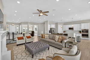 Living room with light wood-style flooring, a chandelier, recessed lighting, ceiling fan, and a textured ceiling