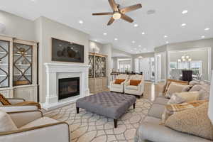 Living area with a glass covered fireplace, a chandelier, wood finished floors, healthy amount of natural light, and recessed lighting