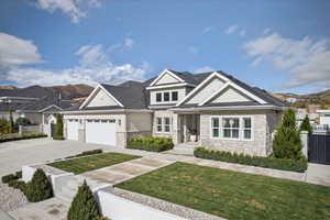 Craftsman-style home with stone siding, concrete driveway, a garage, and a residential view