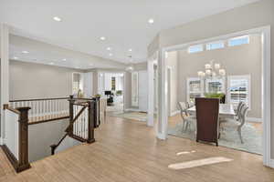Hallway featuring an upstairs landing, a chandelier, light wood-style floors, and recessed lighting
