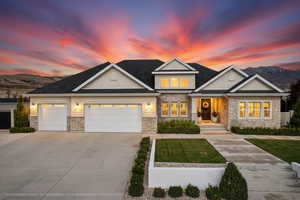 Craftsman-style home featuring stone siding, driveway, a yard, and a garage