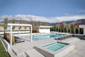 View of swimming pool with an in-ground hot tub, a patio, a mountain view, and a diving board