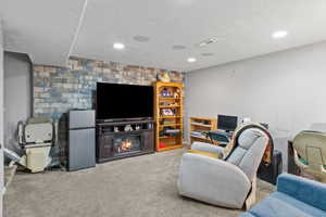 Living room featuring carpet floors, a glass covered fireplace, a textured ceiling, and recessed lighting