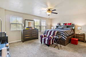 Bedroom with carpet floors, a textured ceiling, and a ceiling fan