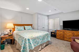 Bedroom featuring light colored carpet, recessed lighting, and a closet