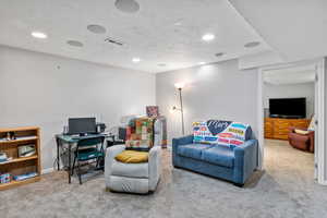 Carpeted living area featuring a textured ceiling and recessed lighting