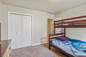 Bedroom featuring a textured ceiling, light carpet, and a closet