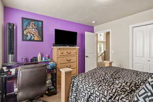 Bedroom with light carpet, a textured ceiling, and a closet