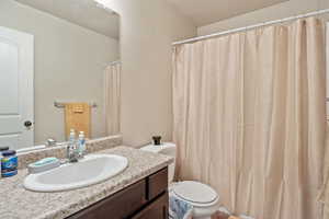 Bathroom with vanity, a shower with shower curtain, and a textured ceiling