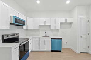 Kitchen with electric range, white cabinetry, dishwashing machine, and recessed lighting