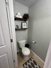 Powder Bathroom with a textured ceiling, light tile patterned floors, and a textured wall
