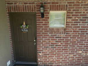 View of front door entry featuring brick siding