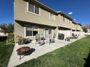 Back view of patio with stucco siding, an outdoor fire pit, a patio, and a yard