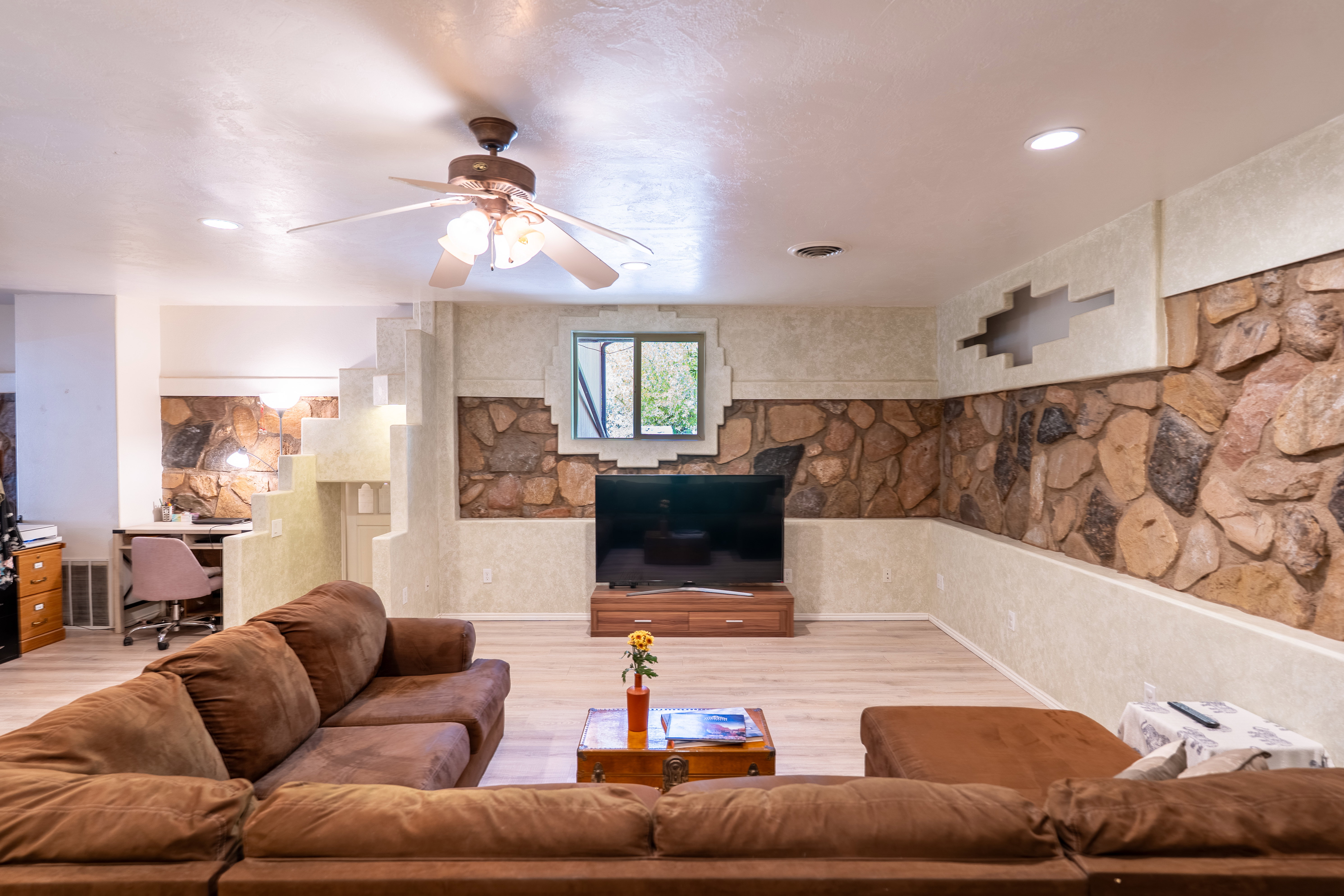Living room featuring an office area, light wood-style floors, and ceiling fan