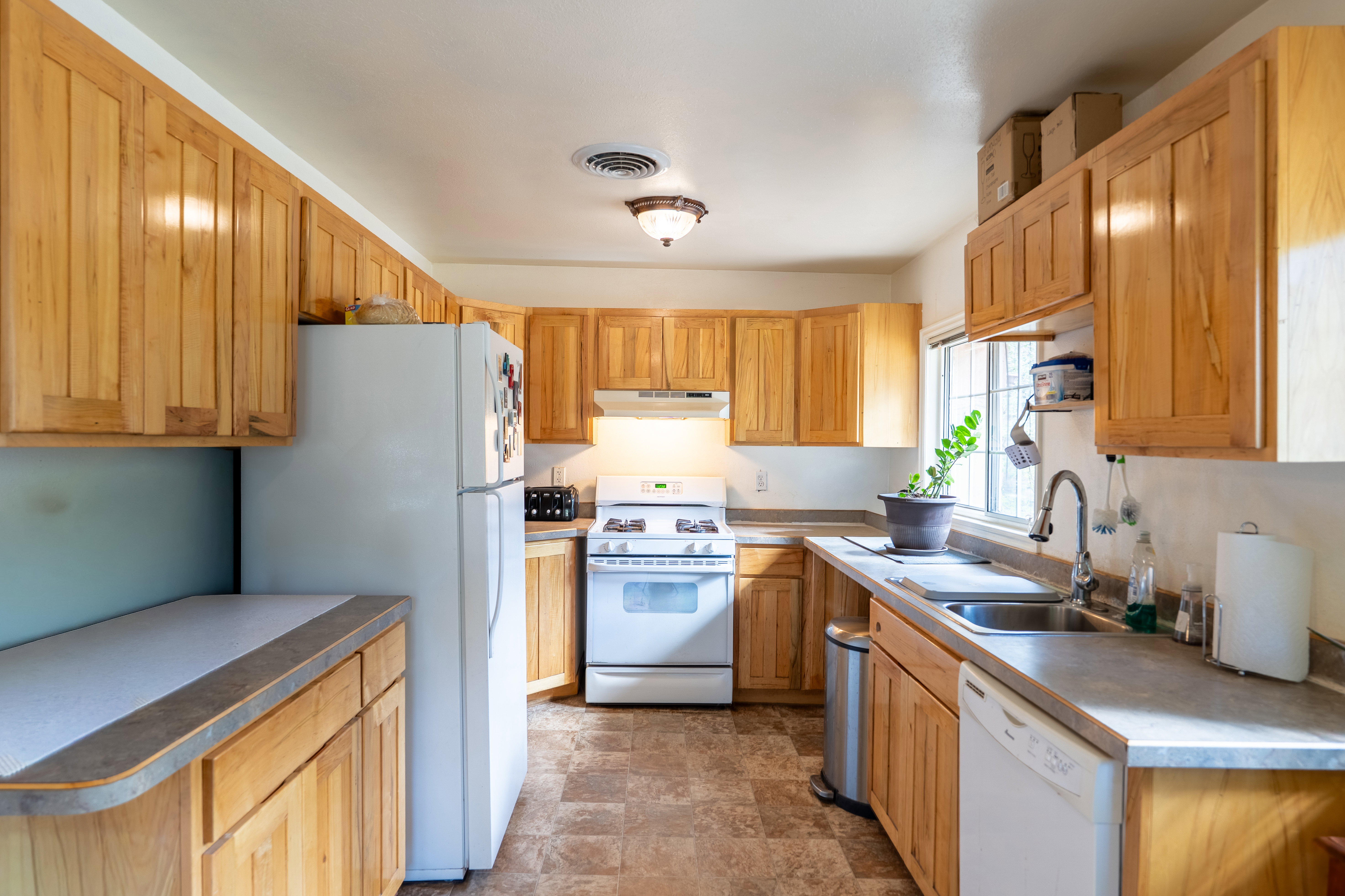 Kitchen featuring white appliances, stone finish floors, and under cabinet range hood