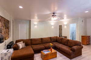 Living room featuring light wood-style flooring, a ceiling fan, and recessed lighting